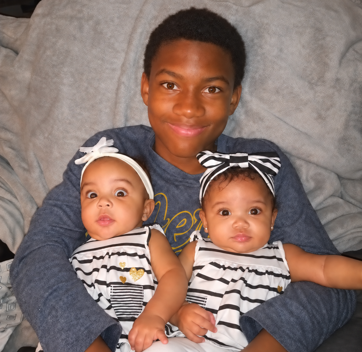 Jelani smiling while holding Eden and Everlee in 2022