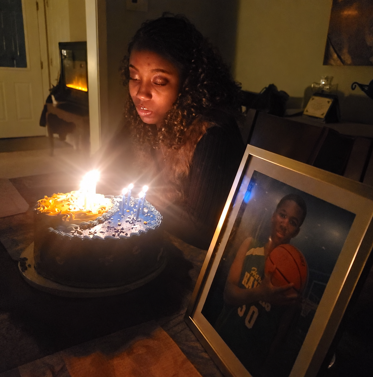 Azaria beside a birthday cake and a portrait of Jelani